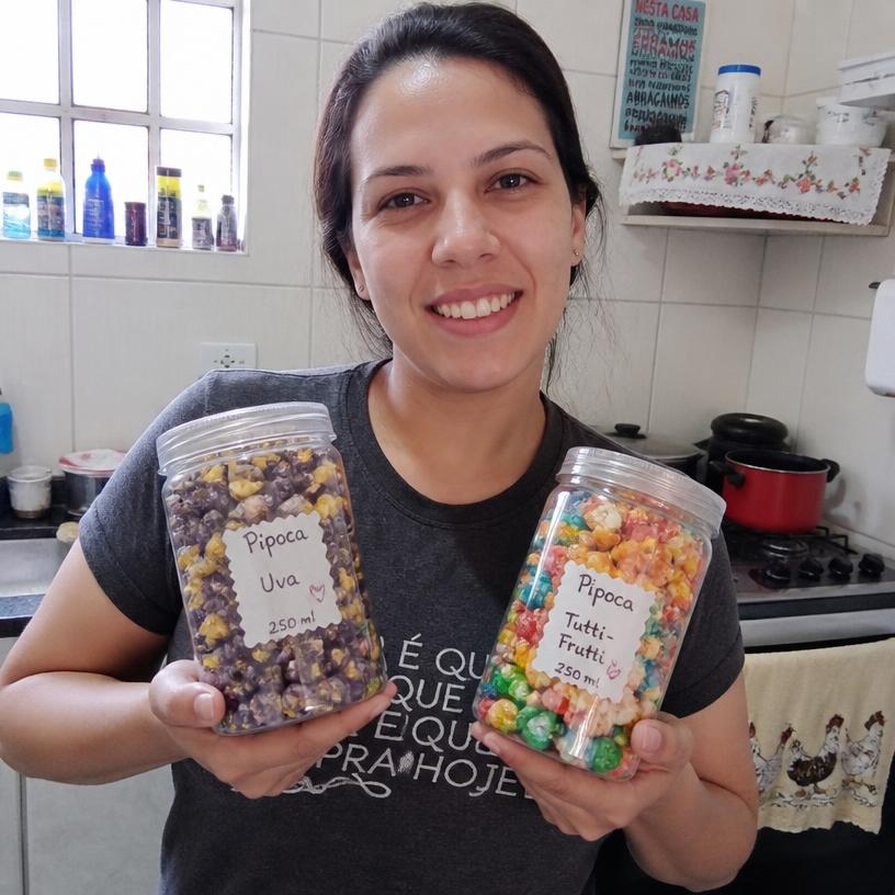 Aluna segurando potes de pipoca gourmet feitos em casa